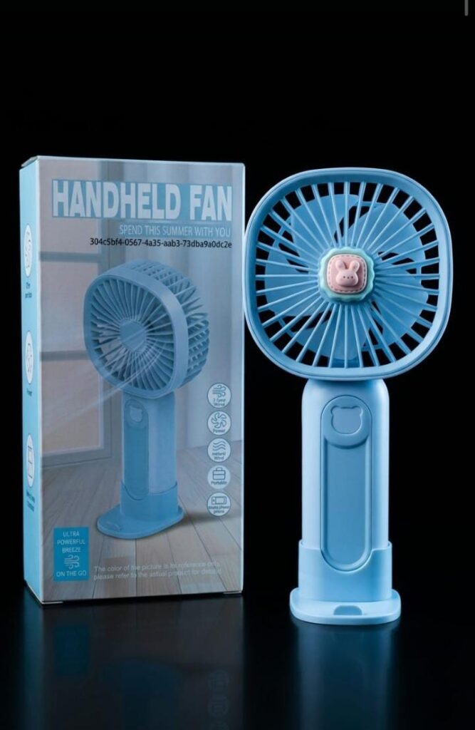 : Light blue portable handheld fan with cute bunny emblem standing next to its box packaging.